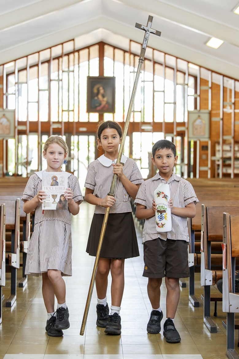 Students processing into the church with candle and bible